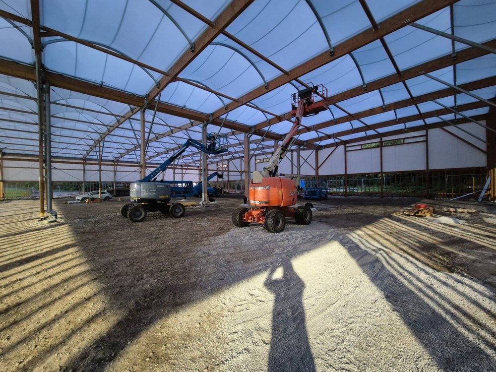 Halle de loisirs de grande portée en charpente bois et couverture textile, en cours de montage